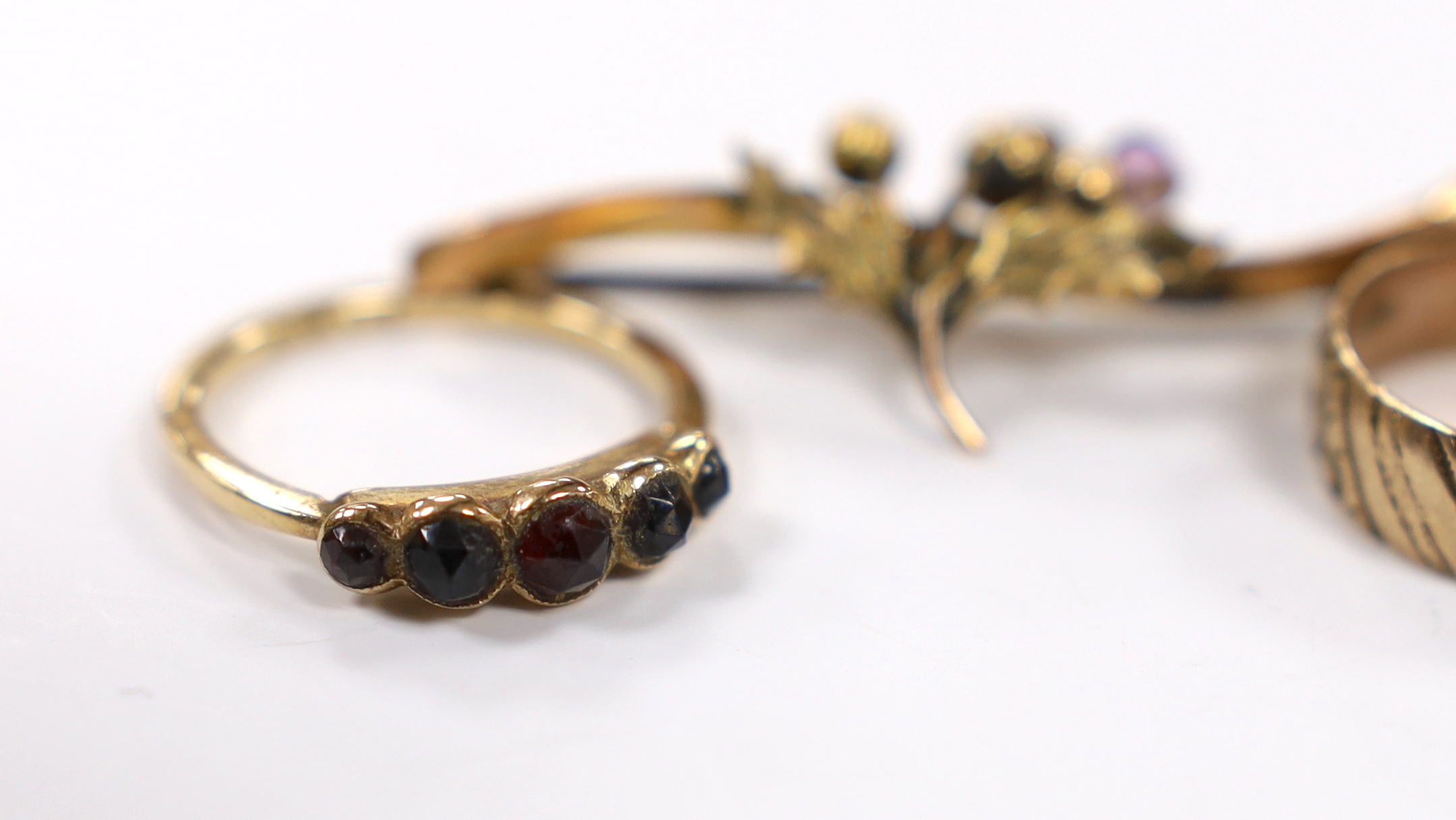 A 9ct and graduated five stone facetted garnet set ring, an engraved 9ct gold band and a 9ct gold and gem set bar brooch (stone missing), gross weight 8.5 grams.